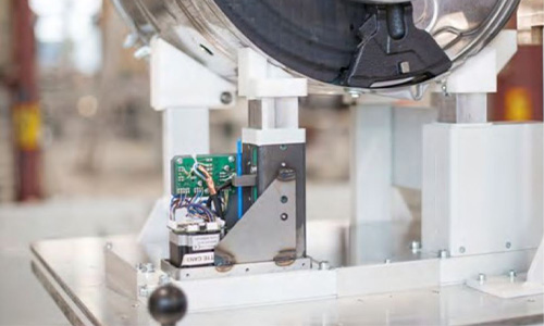 Nahaufnahme von Elektronikkomponenten und einem Metallmechanismus auf einer Maschine oder einem Gerät in einer Industrieumgebung.