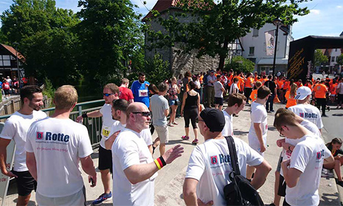 Menschenmenge bei einem Outdoor-Event, viele tragen weißes T-Shirt mit Aufdruck 