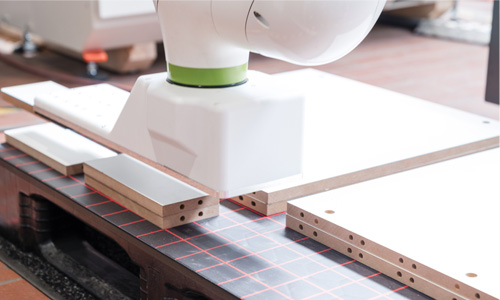 Roboterarm bearbeitet präzise Holzplatten mit Lasermessfeld auf Arbeitstisch in moderner Fertigungsumgebung
