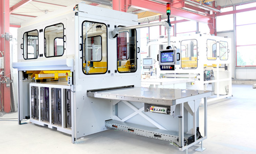 Moderne industrielle Maschine mit mehreren Türen, einem Kontrollpanel mit Bildschirm und einem großen flachen Arbeitstisch in einer hellen Fabrikumgebung