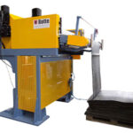 Gelb-blaue Industriemaschine der Firma Rotte mit Hebevorrichtung, die schwarze Platten auf einem Holzpalette ablegt