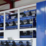 Industrielle Maschine mit blauen und weißen Komponenten in einer Halle mit rotem Stahlträger im Hintergrund