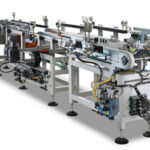 Moderne automatisierte Fertigungsmaschine mit mehreren Förderbändern, Elektromotoren und Steuerungskomponenten auf einem Metallrahmen.