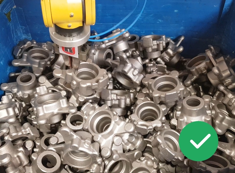 Roboterarm bei der Handhabung von zahlreichen grauen Metallteilen mit runden Öffnungen in einer blauen Kiste