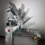 Industriemaschine mit beweglichem Arm, der verschiedene Positionen zeigt, in einem leeren Raum mit grauen Wänden