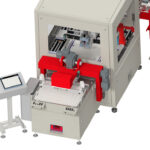 Industrieroboter mit einem grauen Gehäuse und roten mechanischen Halterungen, daneben ein Steuerpult mit Touchscreen auf einem Ständer, weißer Hintergrund.