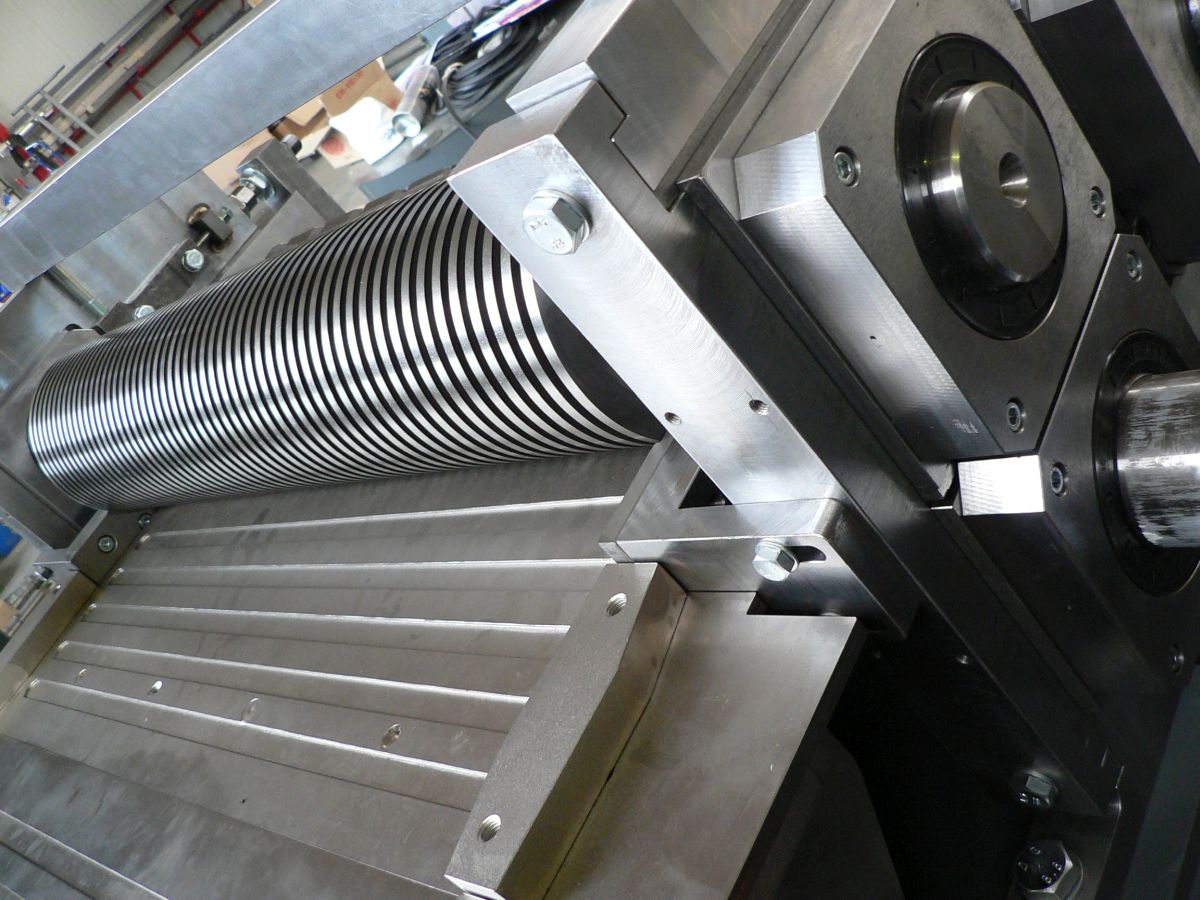 Nahaufnahme einer präzisen Metallwalzen-Maschine mit mehreren silbernen, rotierenden Scheiben und stabilen Befestigungen.