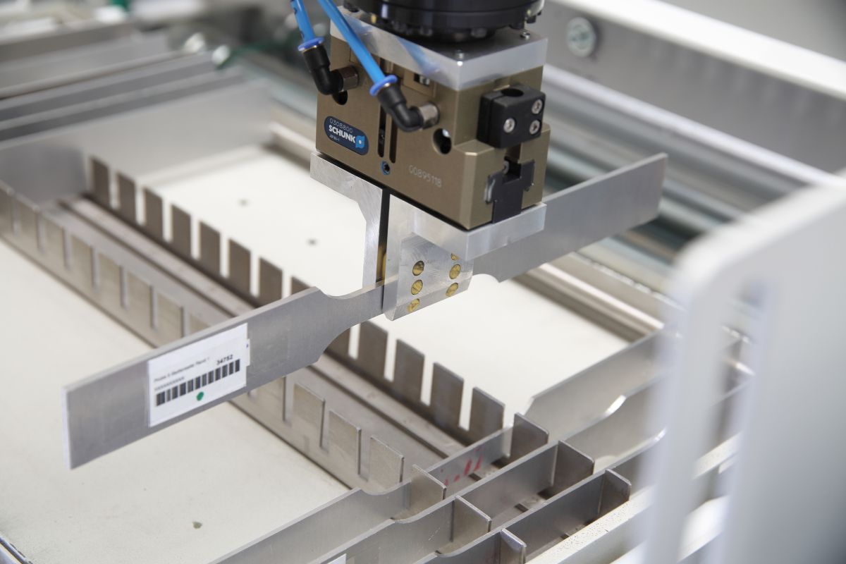 Roboter-Greifarm mit Metallgriff über einer Metallschale in einer Industrieanlage, Marke Schunk sichtbar.