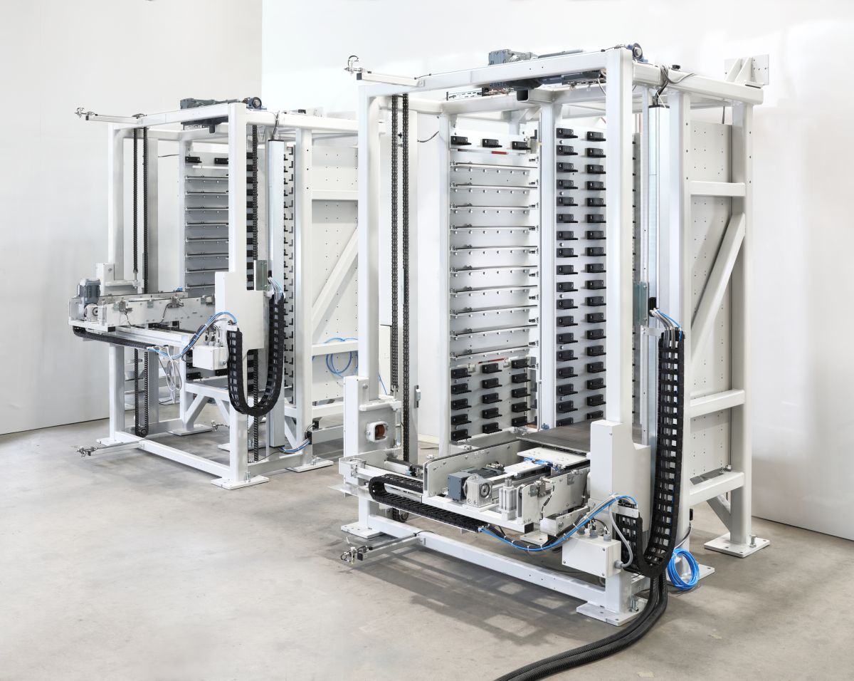 Industrielle Hebe- und Transportsysteme mit mehreren Ketten und Rahmen, auf Betonboden in einer Halle installiert.