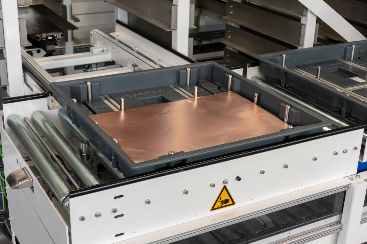 Industrielle Maschine mit Förderband und Blecheinsatz, Warnschild für heiße Fläche an der Vorderseite.