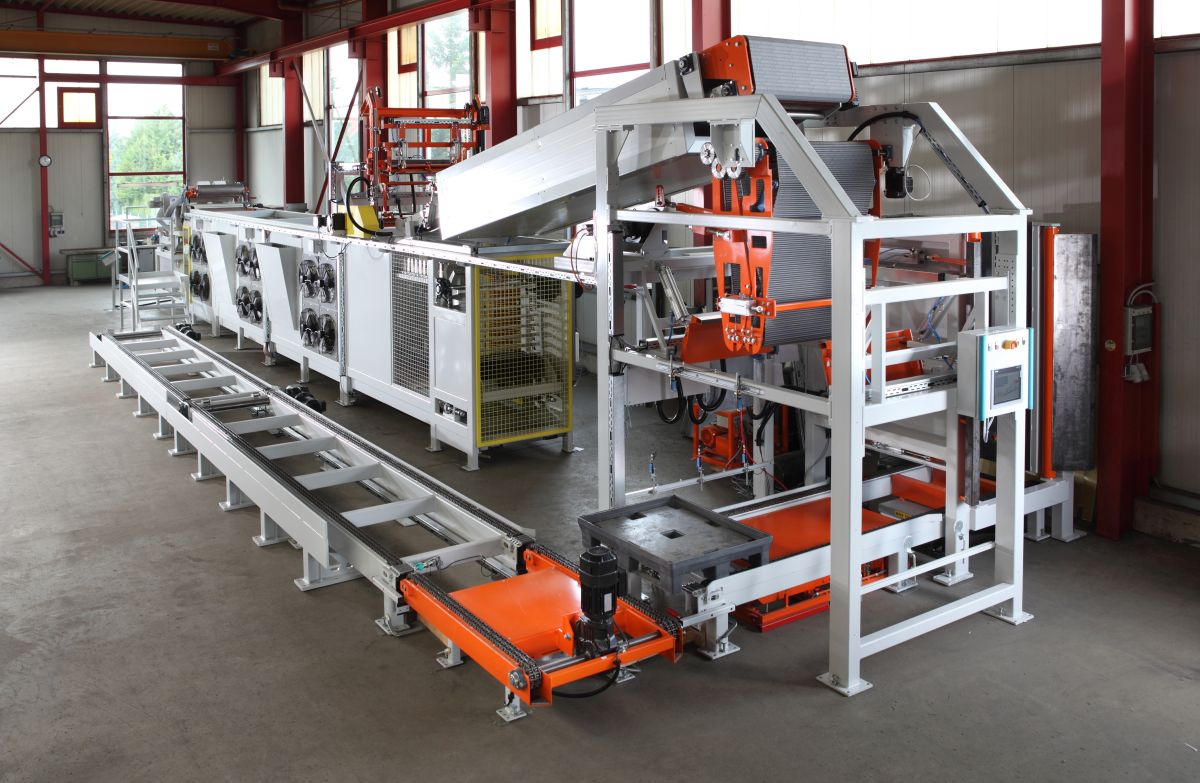 Industrielle Fertigungsmaschine aus Metall mit Förderband und Steuerung in einer Werkhalle