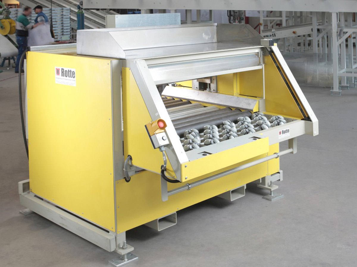 Gelbe Industriewaffelmaschine mit Metallrollen und Steuerknopf in Fabrikumgebung mit unscharfen Personen im Hintergrund