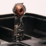 Nahaufnahme zweier Metallkontakte mit kupferfarbenen Anschlüssen in einem elektrischen Bauteil oder einer Batteriehalterung.