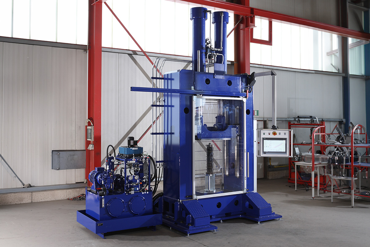 Große blaue industrielle Hydraulikprüfmaschine mit Steuerterminal in Halle mit weißem und rotem Metallrahmen